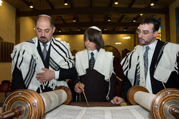 2 men and a boy looking at a scroll